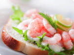 Oregon Pink shrimp on a slice of fresh white bread with green leaf lettuce, an aioli spread, and fresh dill. 